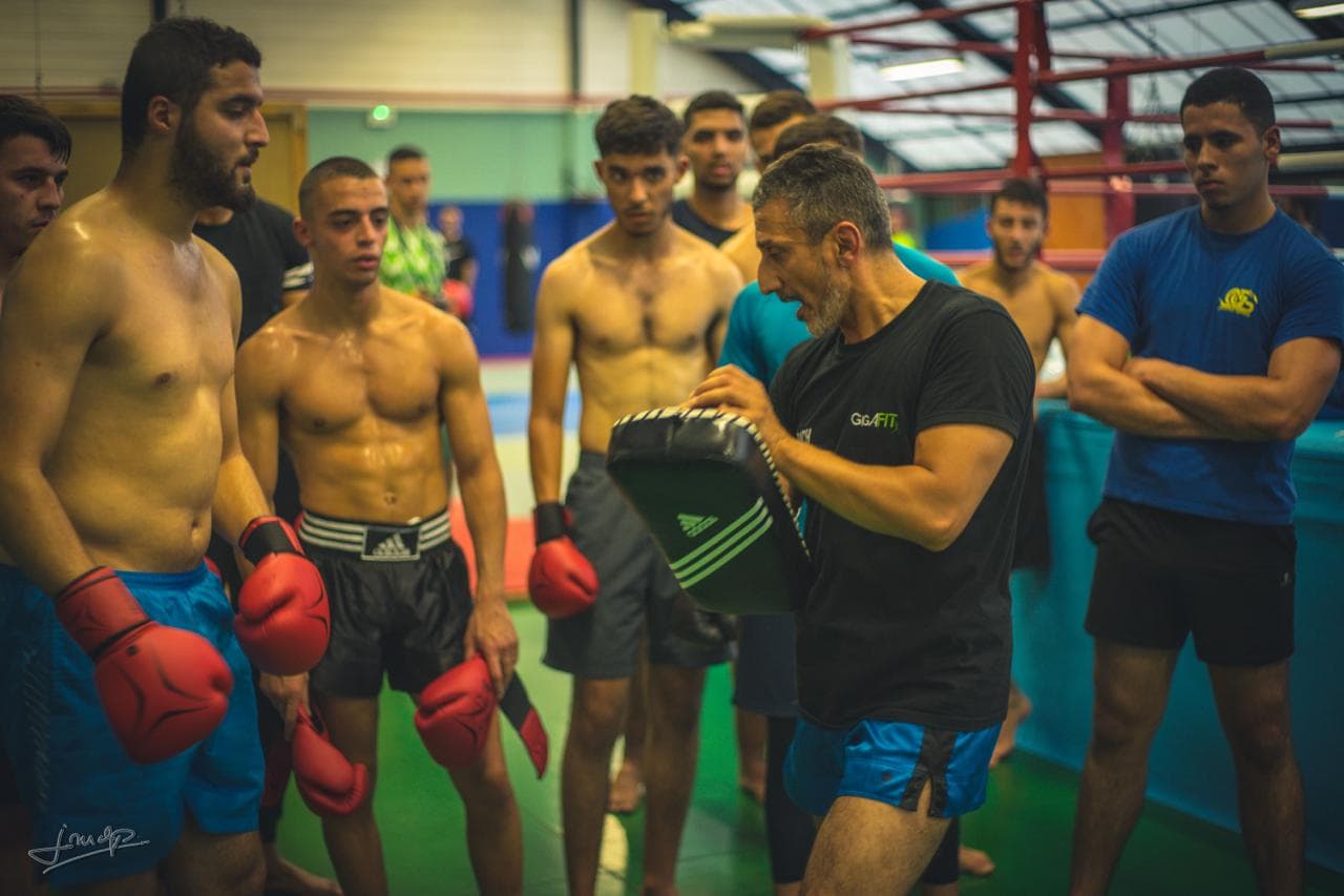 Le coach du club OGS Arts Martiaux au travail aux pattes d'ours avec le groupe